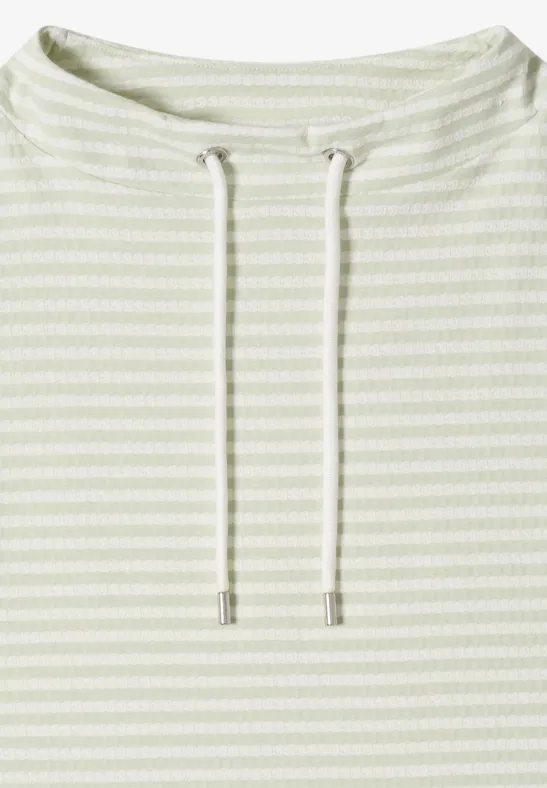 Pull léger rayé vert pâle avec cordons à l'encolure.