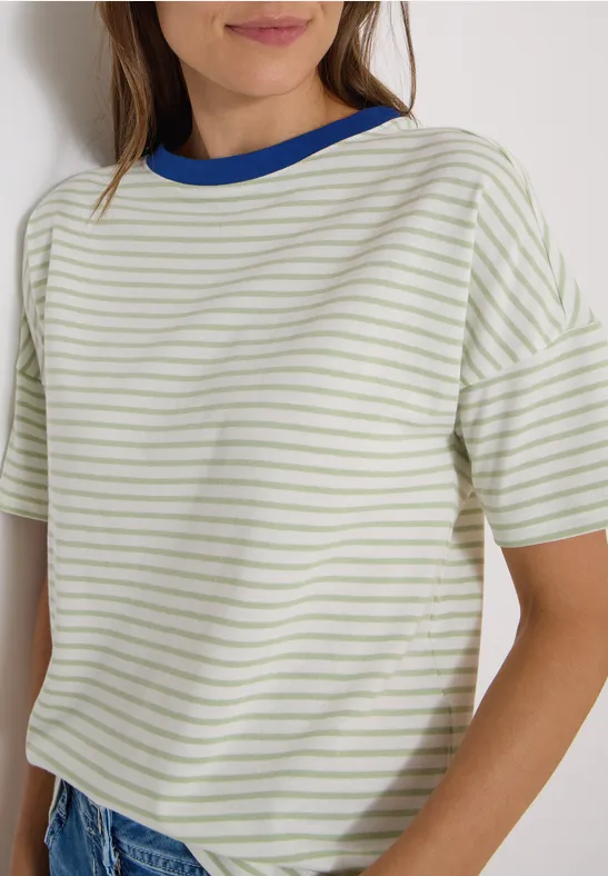 Frau in hellgrün-weiß gestreiftem T-Shirt mit blauem Kragen und Jeans, seitlich zu sehen.