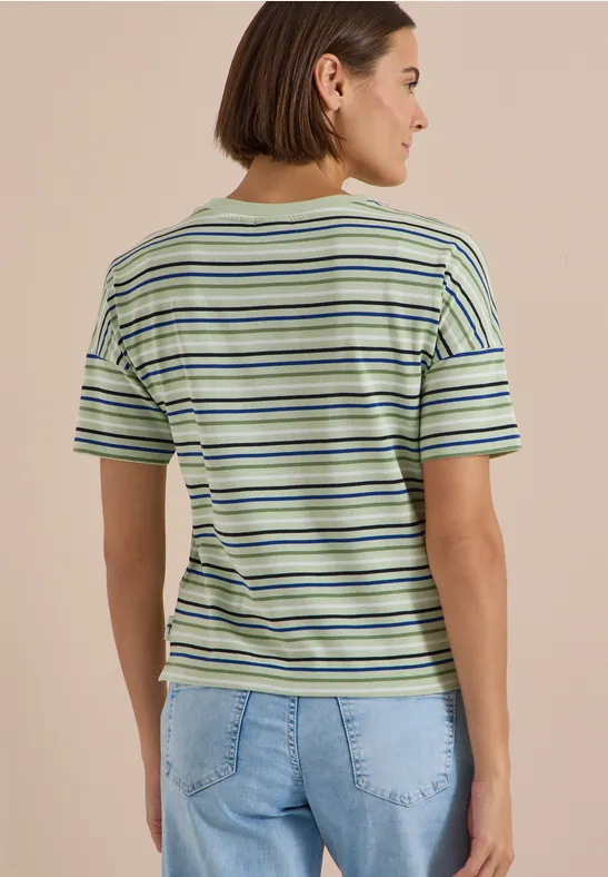 Achteraanzicht van een vrouw in een groen-wit-blauw gestreept T-shirt en lichtblauwe jeans.