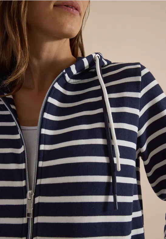 Een persoon draagt een blauw-wit gestreepte hoodie met rits.