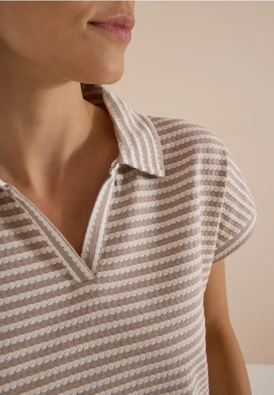Close-up van een vrouwentorso in een beige gestreept poloshirt, gezicht buiten beeld.