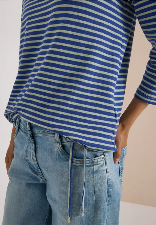 Personne porte un t-shirt à manches longues bleu à rayures blanches avec cordon et jean clair.