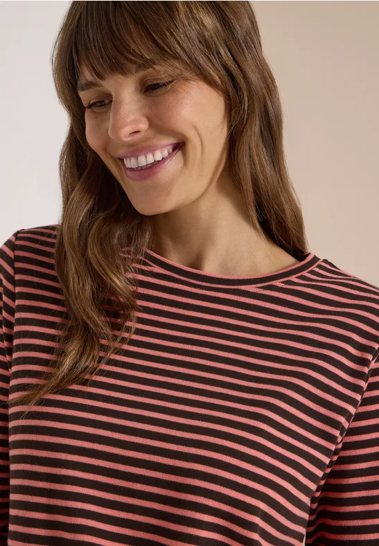 Femme souriante aux cheveux bruns portant un t-shirt rayé.