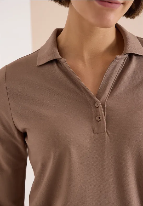 Nahaufnahme einer Person in braunem Poloshirt mit offenem Kragen und Knopfleiste.