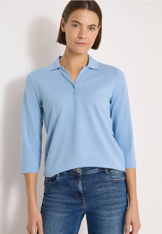 Eine Person trägt ein hellblaues Poloshirt mit 3/4-Ärmeln und Jeans.