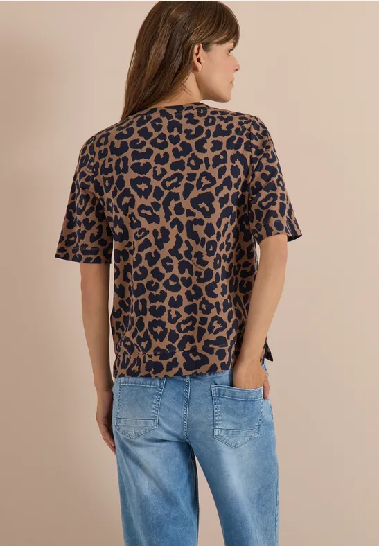 Frau von hinten in locker sitzendem T-Shirt mit leo Muster und blauen Jeans