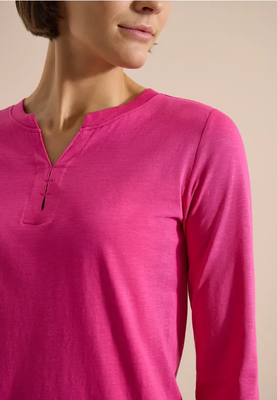 Damen-Oberteil in knalligem Pink mit langen Ärmeln und kleinem V-Ausschnitt.