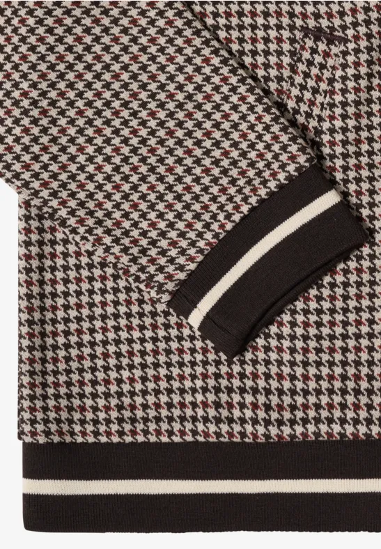 Close-up van een trui met zwart-wit-rood pied-de-poule motief en gestreepte boord in wit.