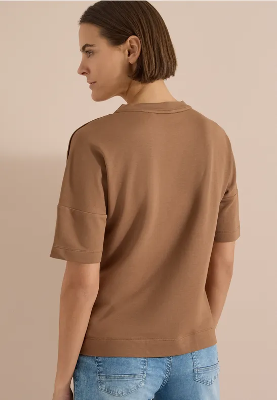 Vue arrière d'une femme portant un haut marron à manches courtes et un jean bleu