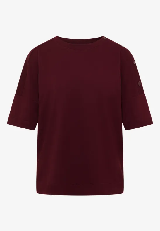 Un t-shirt bordeaux uni, col rond et manches mi-longues.