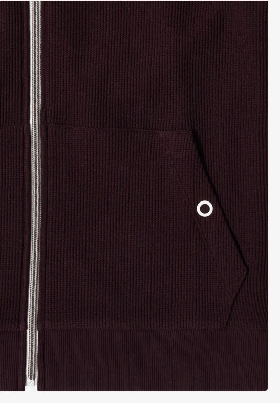 Close-up van een bordeaux hoodie met rits en zak aan de voorkant