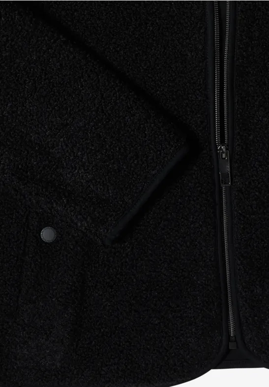 Detailaufnahme einer schwarzen Fleecejacke mit Reißverschluss, Druckknopf und weicher, strukturierter Oberfläche.