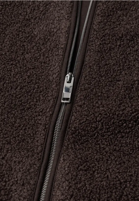 Close-up van een zilveren rits op bruin fleece.