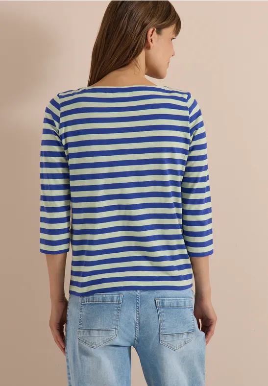 Vrouw van achteren in een blauw-wit gestreept 3/4-mouwshirt en een blauwe spijkerbroek.
