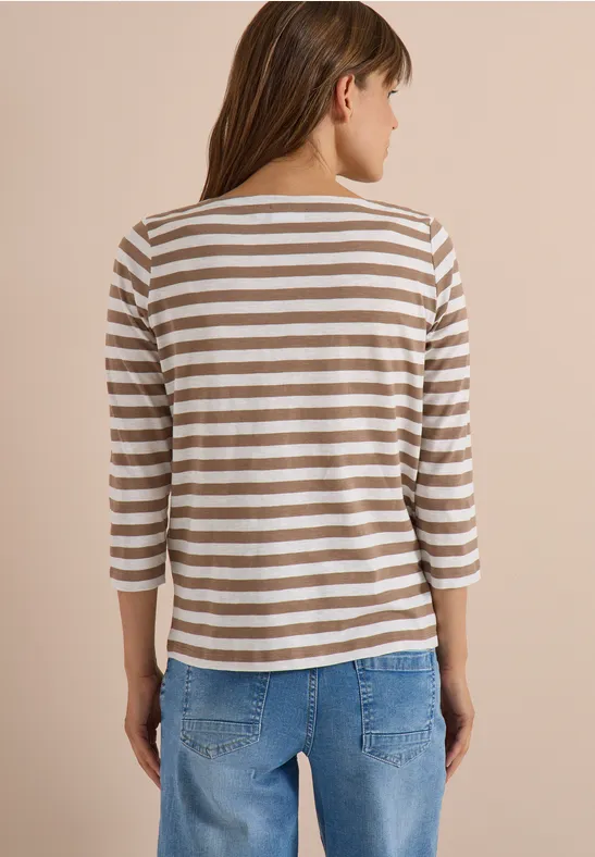 Frau von hinten in gestreiftem Dreiviertelarm-Shirt und blauen Jeans vor neutralem Hintergrund.