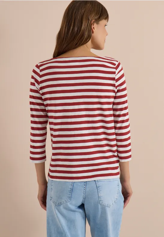 Vrouw van achteren in een rood-wit gestreept 3/4-mouwshirt en lichtblauwe spijkerbroek.
