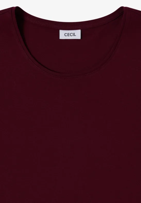 Un t-shirt uni bordeaux à col rond, avec l’étiquette de la marque « Cecil » cousue à l’intérieur du col.