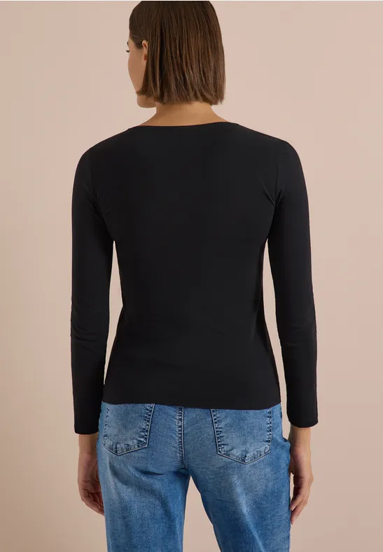 Femme vue de dos portant un t-shirt à manches longues noir et un jean bleu.