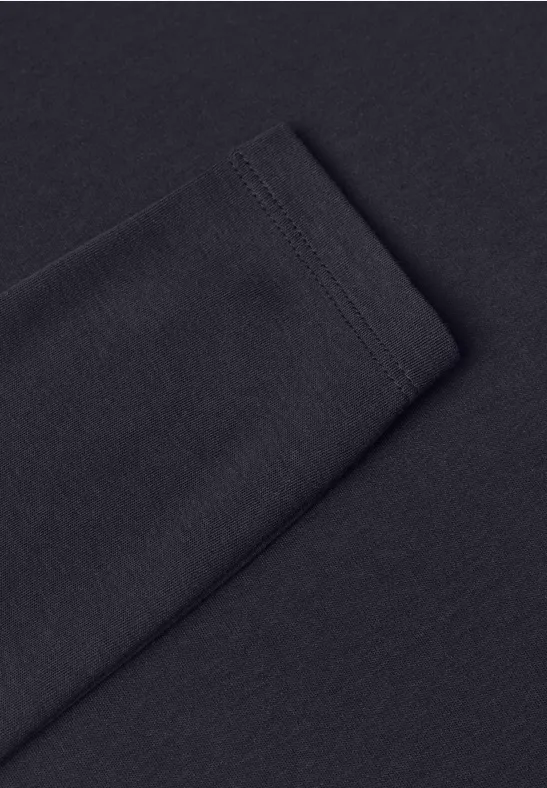 Nahaufnahme eines schwarzen Langarmshirts mit sichtbarer Naht am Ärmel auf einfarbigem Hintergrund.