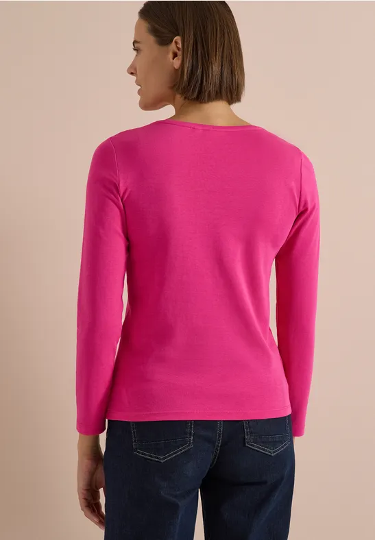 Person von hinten in pinkem Langarm-Pullover und dunkler Jeans