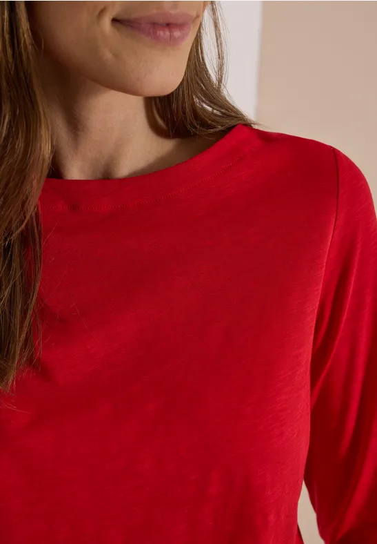 Teilansicht einer Frau in rotem Langarmshirt.