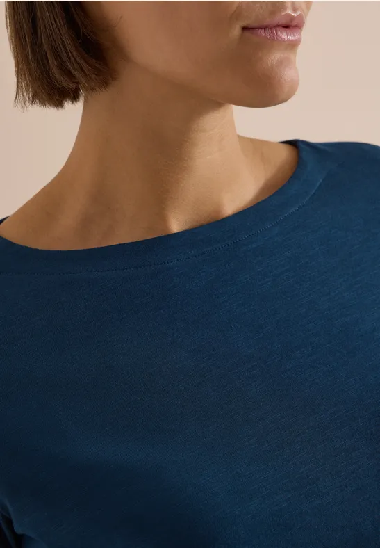 Nahaufnahme einer Person, die ein dunkelblaues T-Shirt trägt, von Hals bis Schulter.