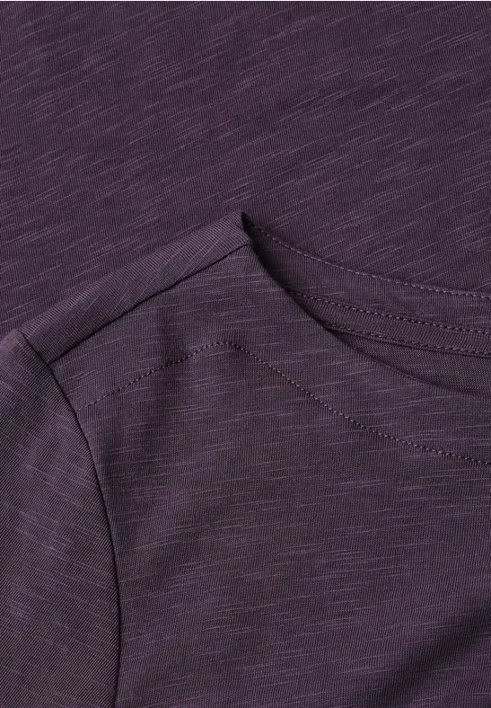 Nahaufnahme eines lila T-Shirts mit Rundhalsausschnitt und Schulterpartie.