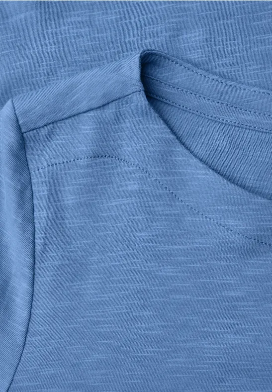 Nahaufnahme eines ärmellosen, hellblauen Shirts mit feiner Slub-Struktur.