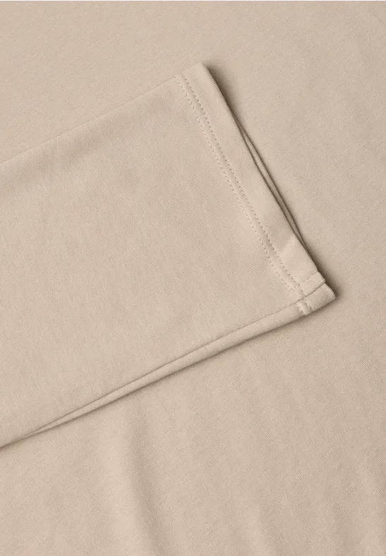 Beige Stoff oder T-Shirt mit sichtbarer Naht, leicht gefaltet auf glattem Untergrund