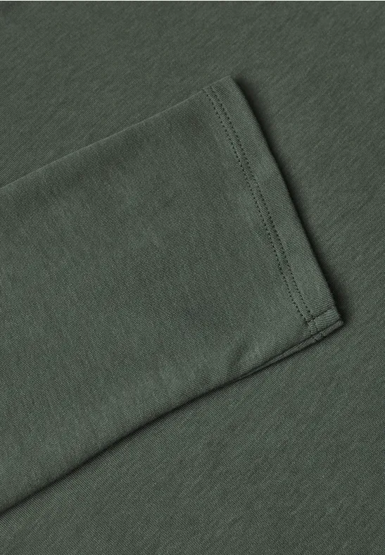 Close-up van de zoom van een donkergroene katoenen T-shirtmouw met nette stiknaad.