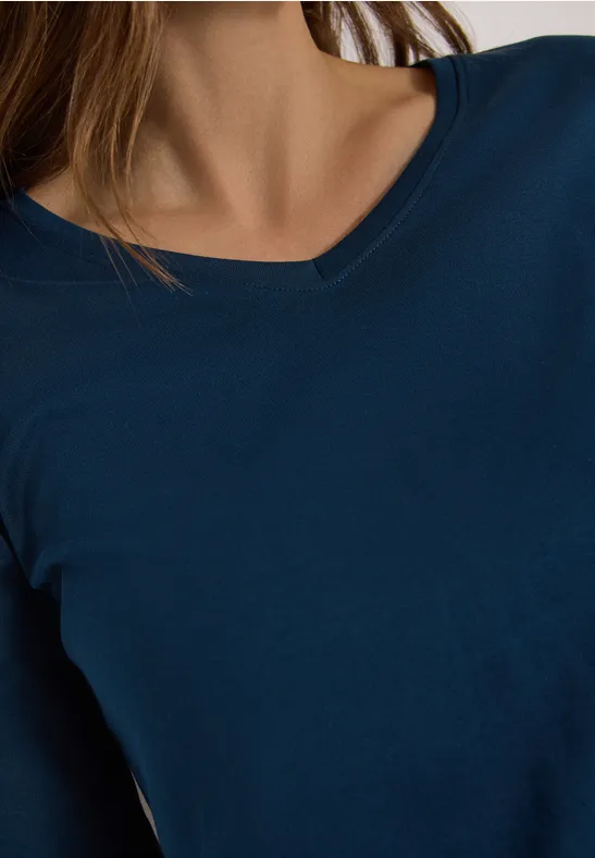 Ausschnitt eines blauen V-Ausschnitt-Shirts an einer Person, nur Oberkörper.