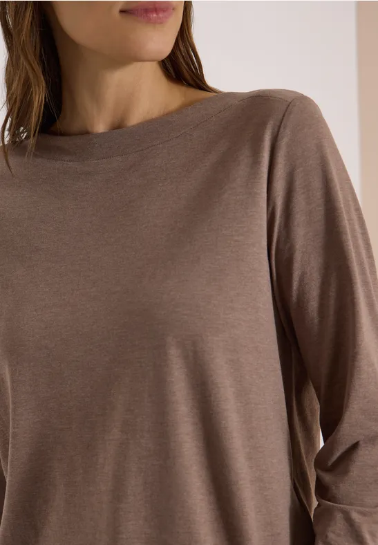Persoon draagt een eenvoudig bruin shirt met lange mouwen, zijaanzicht.