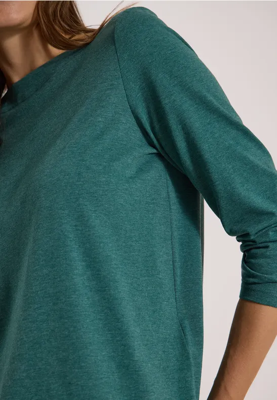 Person im dunkelgrünen Langarmshirt, Fokus auf Oberkörper und Arm.