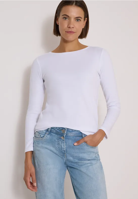 Frau in weißem Langarmshirt und blauen Jeans.