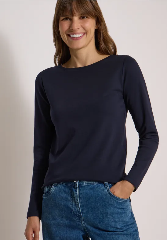 Lächelnde Frau in dunkelblauem Langarmshirt und Jeans