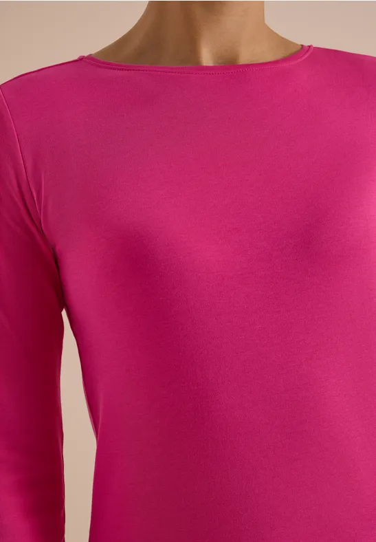 Nahaufnahme eines torsos in einem pinken, eng anliegenden Oberteil.