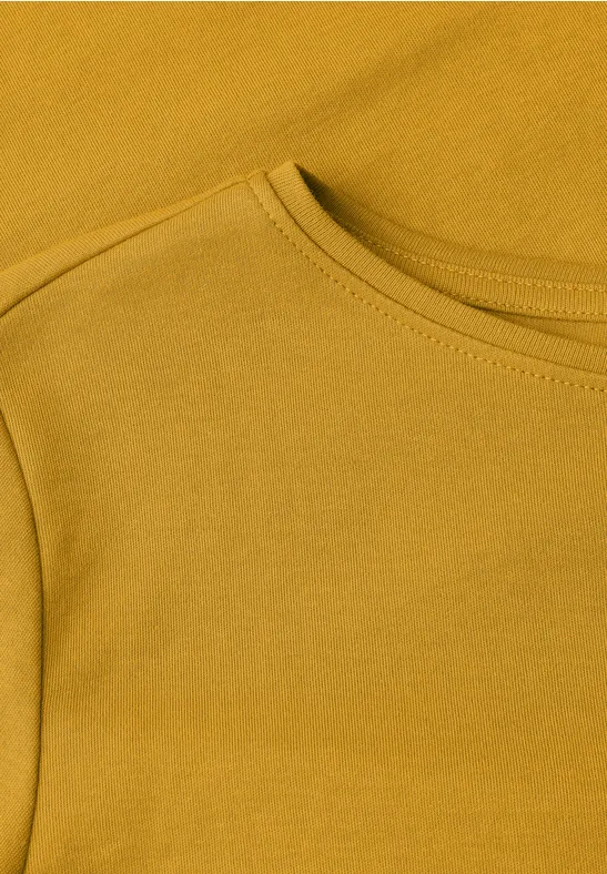 Nahaufnahme eines senfgelben T-Shirts mit Rundhalsausschnitt