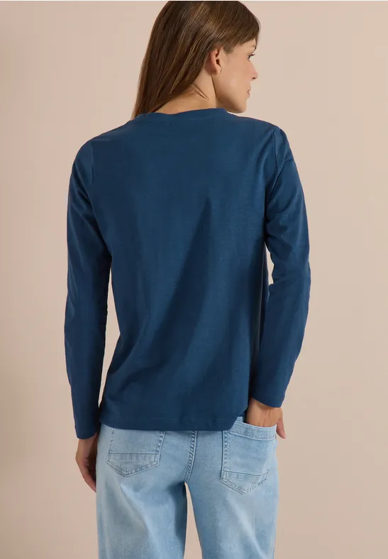 Frau von hinten in blauem Langarmshirt und hellen Jeans