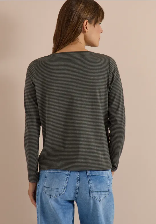 Une personne vue de dos porte un t-shirt à manches longues vert foncé à fines rayures et un jean bleu.