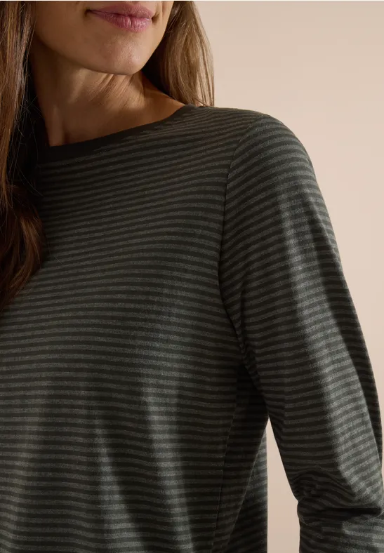 Gros plan sur une personne portant un t-shirt à manches longues à fines rayures sombre sur fond neutre.