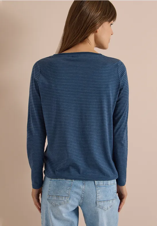 Frau von hinten in blau gestreiftem Langarmshirt und hellblauen Jeans.
