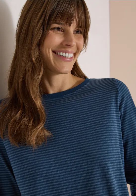 Eine lächelnde Frau in blau-gestreiftem Shirt
