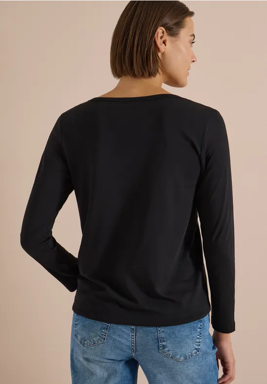 Rückansicht einer Frau in schwarzem Langarmshirt und blauer Jeans.