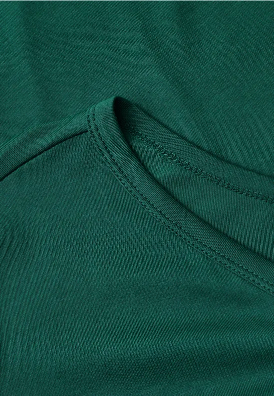Close-up van de halslijn van een groen T-shirt met zichtbare naad