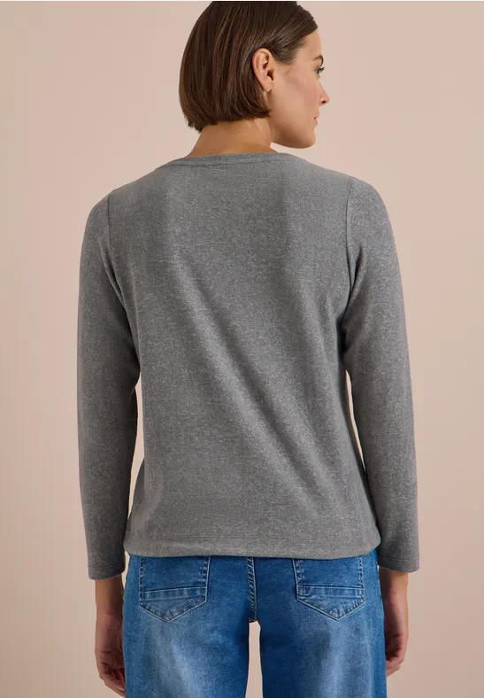 Rückansicht einer Person in grauem Langarm-Pullover und blauen Jeans.