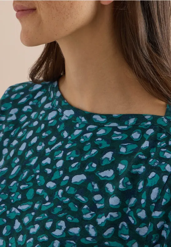 Une femme porte un haut bleu-vert à motif léopard abstrait
