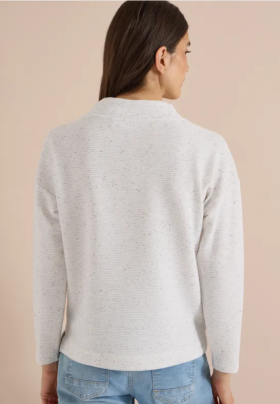 Rückenansicht einer Frau im hellen, melierten Pullover mit langen braunen Haaren.