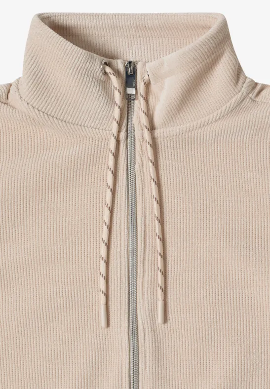 Beige, gerippter Pullover mit hohem Kragen, durchgehendem Reißverschluss und Kordelzügen an der Halsöffnung.