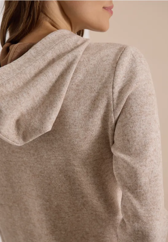 Rückenansicht einer Person, die einen beigen, melierten Kuschel-Hoodie aus weichem Strickstoff trägt.