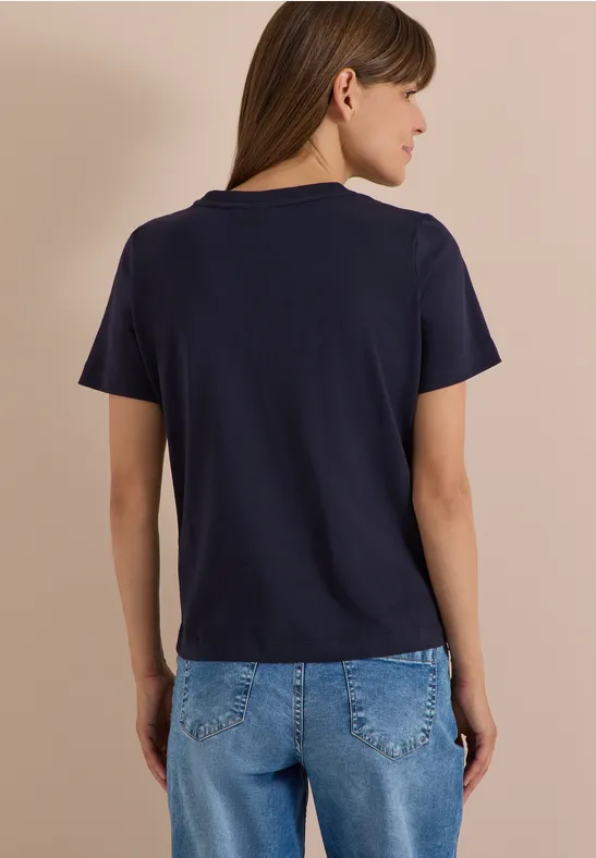 Personne de dos en t-shirt bleu marine et jean sur fond beige.